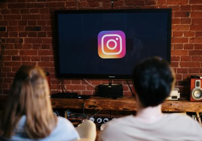 客厅电视屏幕上显示 Instagram 应用图标，两人坐在沙发上观看