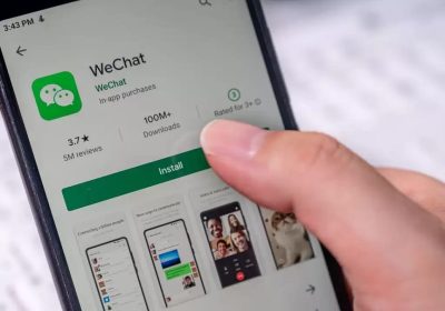 一只手握着安卓手机，屏幕上显示应用商店中的微信安装页面