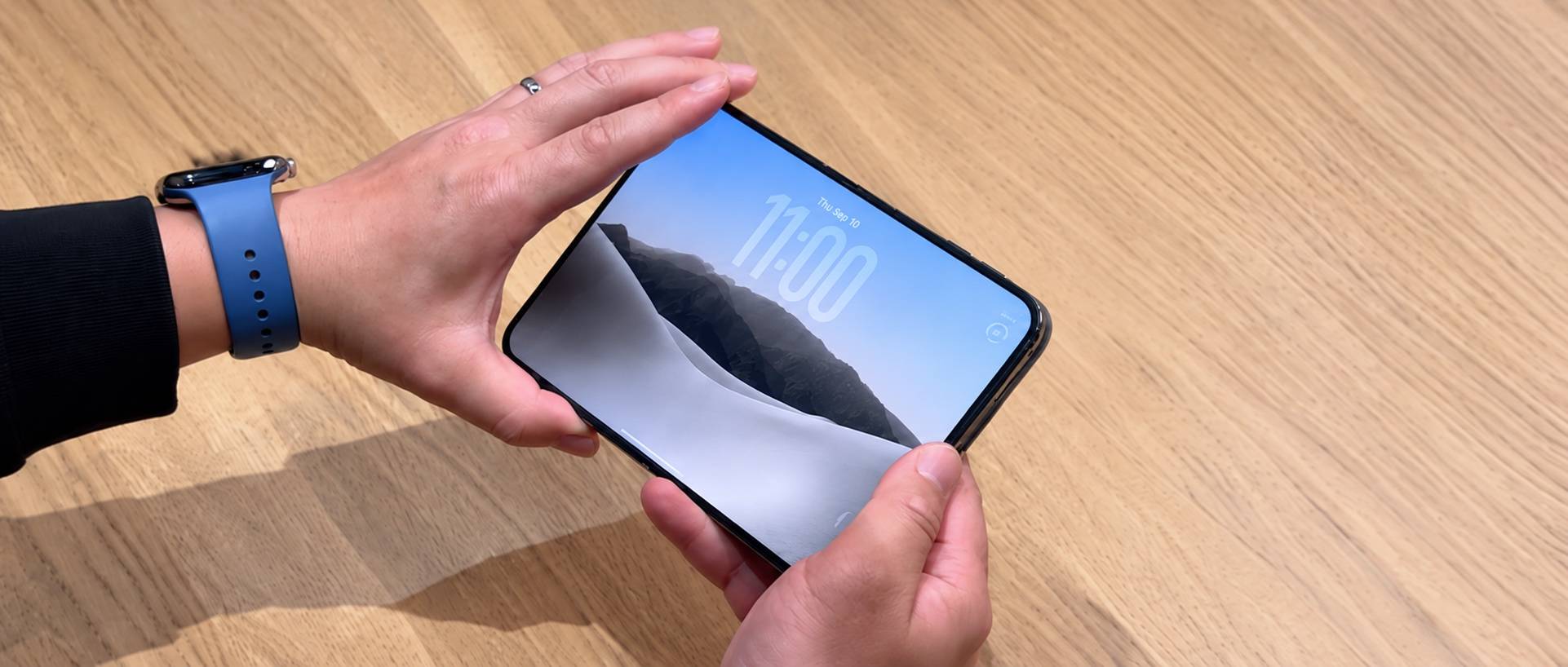 双手在木桌上操作折叠屏iPhone