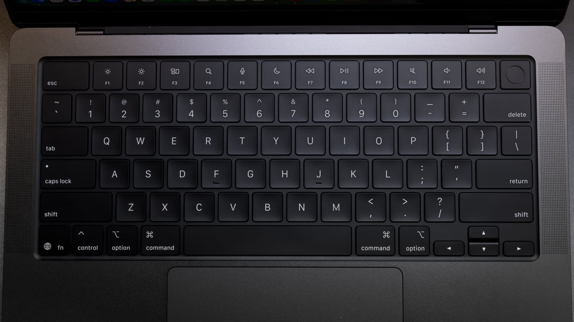 MacBook Pro 键盘与触控板特写,深空黑机身细节
