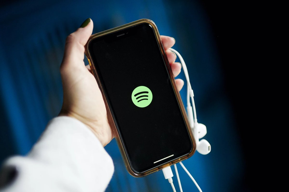 手持手机屏幕显示 Spotify 标志