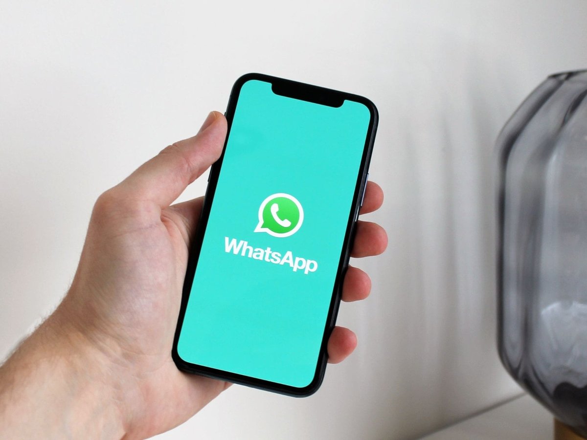 手持 iPhone,屏幕显示 WhatsApp 标志