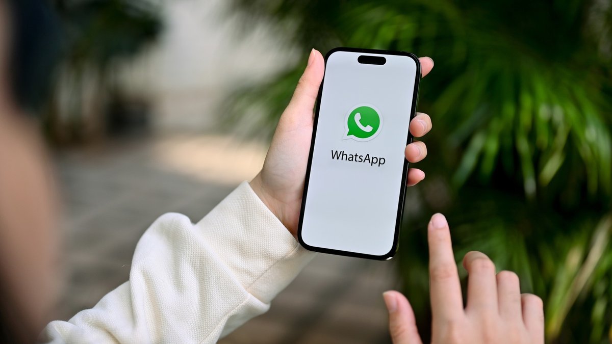 双手操作打开 WhatsApp 聊天界面的 iPhone